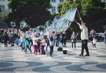 A group of people playing bubble soccer in a park, running and bouncing inside large inflatable bubbles.